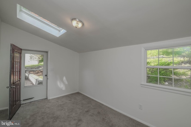 carpeted empty room featuring lofted ceiling with skylight