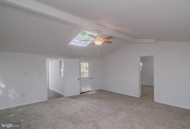 empty room with light carpet, ceiling fan, and vaulted ceiling with skylight