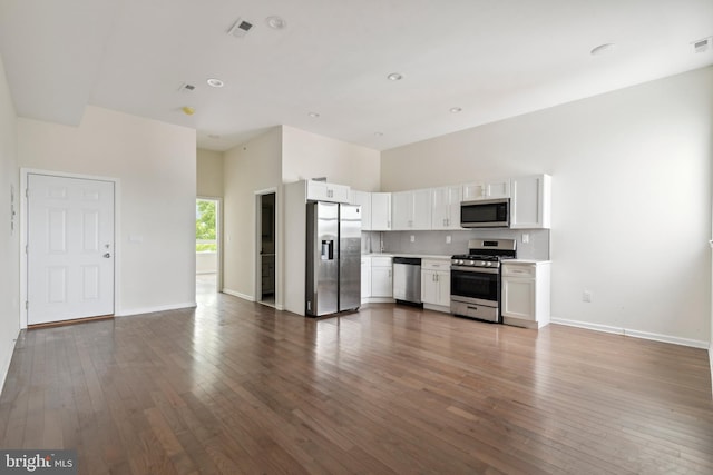 kitchen featuring hardwood / wood-style floors, white cabinetry, appliances with stainless steel finishes, and a towering ceiling