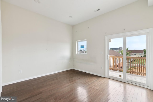 empty room with dark hardwood / wood-style floors and a wealth of natural light