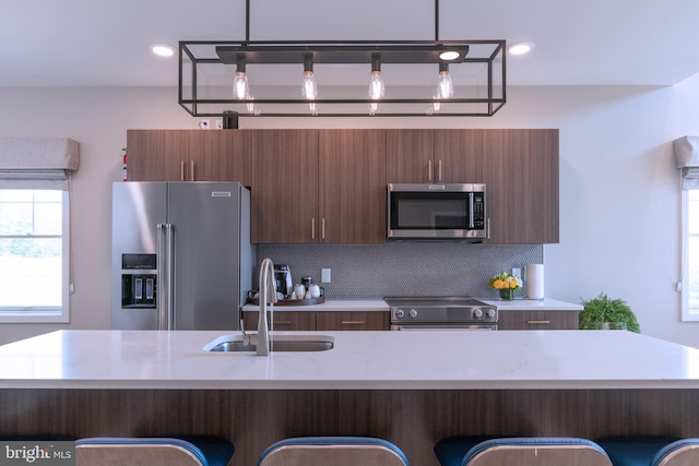 kitchen with tasteful backsplash, decorative light fixtures, stainless steel appliances, and sink