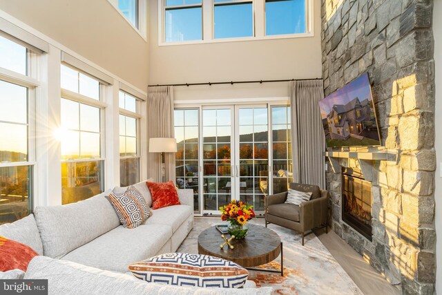 living room with a towering ceiling and a stone fireplace