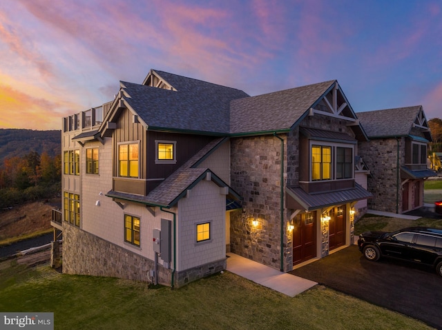 view of front of home with driveway, a shingled roof, an attached garage, and stone siding