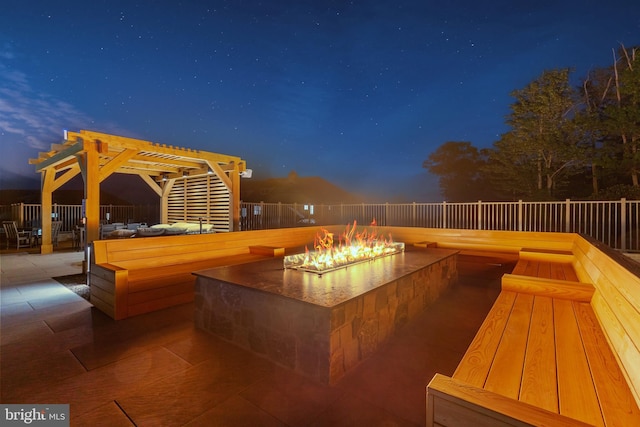 patio at twilight with a fire pit and a pergola