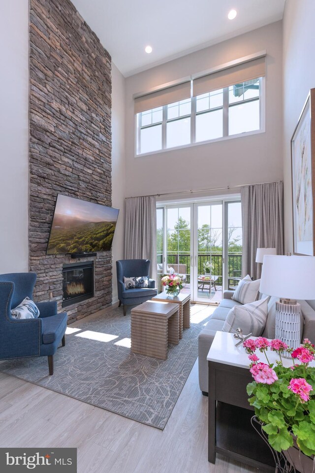 living room with a towering ceiling, hardwood / wood-style floors, and a fireplace