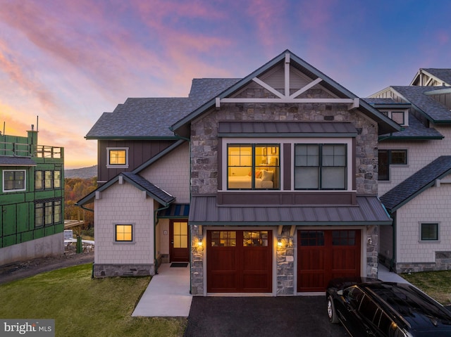 view of front of house featuring metal roof, aphalt driveway, a garage, roof with shingles, and a standing seam roof