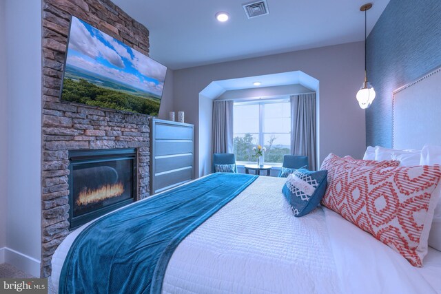 bedroom featuring a stone fireplace