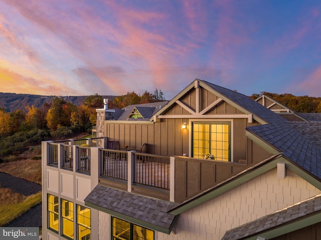 back of property featuring a shingled roof, board and batten siding, and a balcony