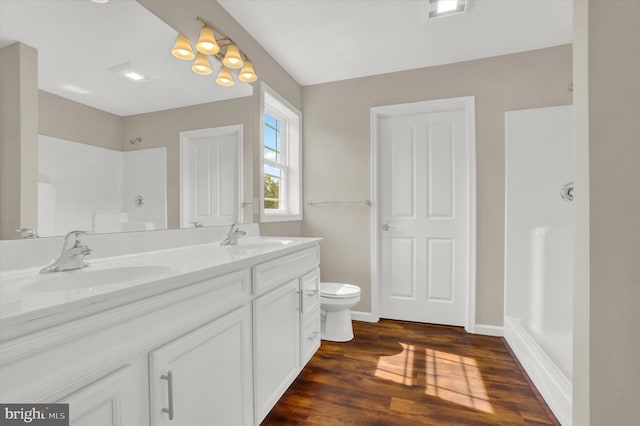 bathroom with hardwood / wood-style flooring, vanity, toilet, and a shower