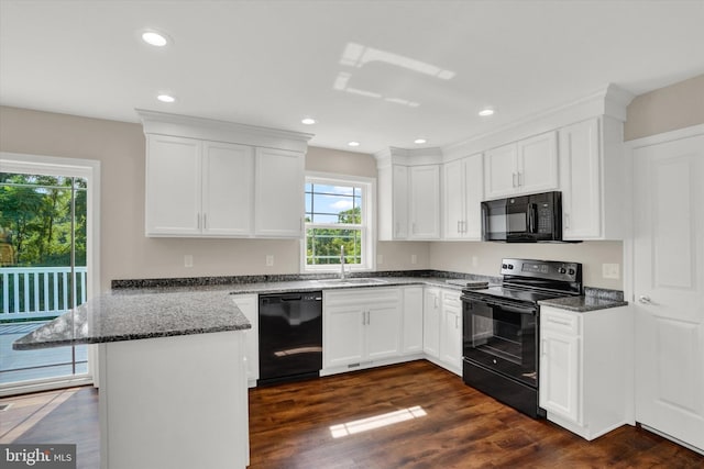 kitchen with black appliances, dark hardwood / wood-style floors, kitchen peninsula, a wealth of natural light, and white cabinets