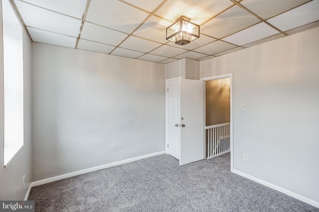 carpeted empty room with a paneled ceiling