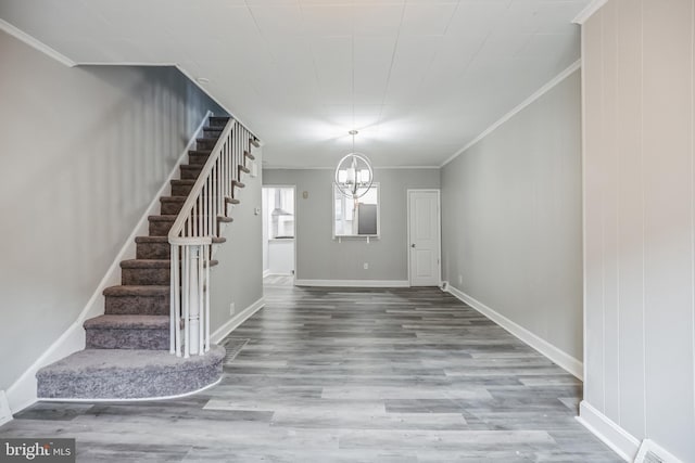 foyer entrance featuring hardwood / wood-style floors, a chandelier, and ornamental molding