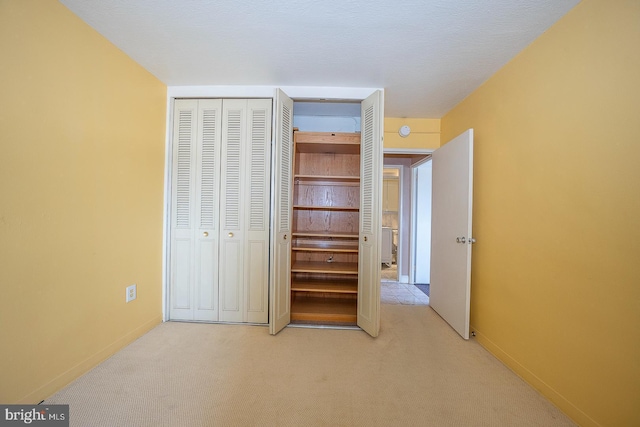 unfurnished bedroom featuring light colored carpet and a closet