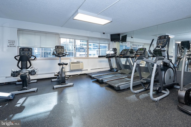 gym with an AC wall unit and a textured ceiling