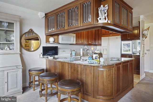 kitchen featuring light stone countertops, sink, kitchen peninsula, white appliances, and ornamental molding