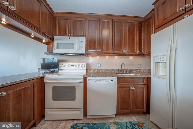 kitchen with light stone counters, white appliances, sink, and light tile patterned floors