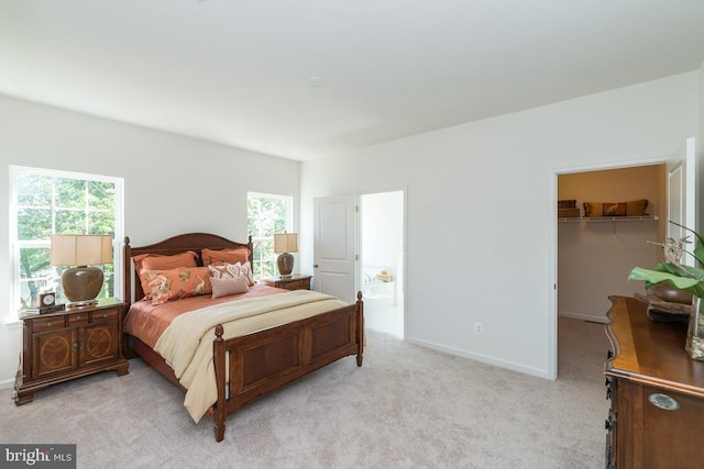 bedroom with light carpet, a walk in closet, and a closet