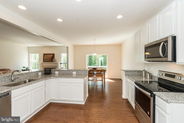 kitchen with appliances with stainless steel finishes, dark hardwood / wood-style floors, decorative light fixtures, and a healthy amount of sunlight