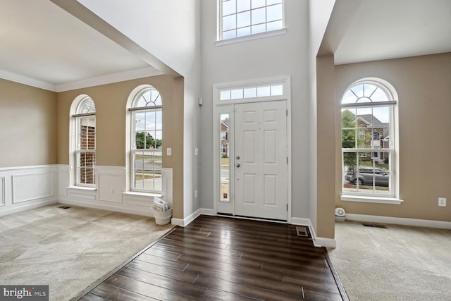 foyer with dark carpet and ornamental molding