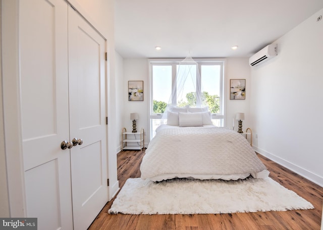 bedroom with hardwood / wood-style flooring, a closet, and a wall mounted AC