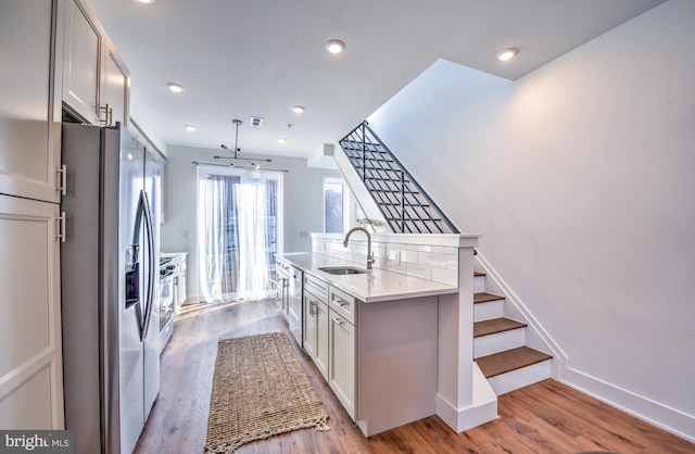 kitchen featuring decorative light fixtures, light hardwood / wood-style floors, sink, stainless steel appliances, and white cabinets