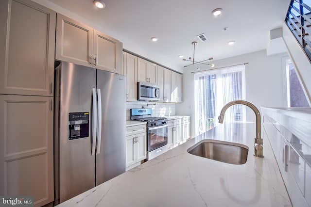 kitchen featuring decorative backsplash, light stone countertops, sink, and stainless steel appliances