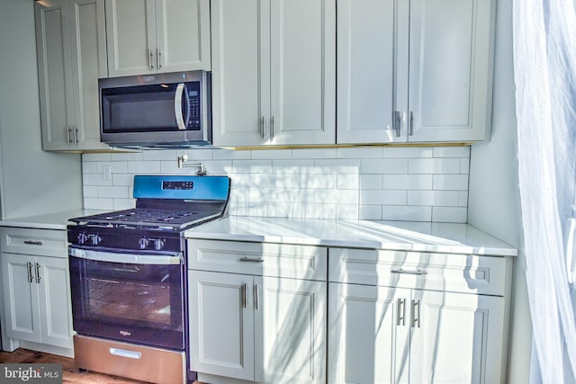 kitchen with white cabinets, decorative backsplash, appliances with stainless steel finishes, and dark hardwood / wood-style floors