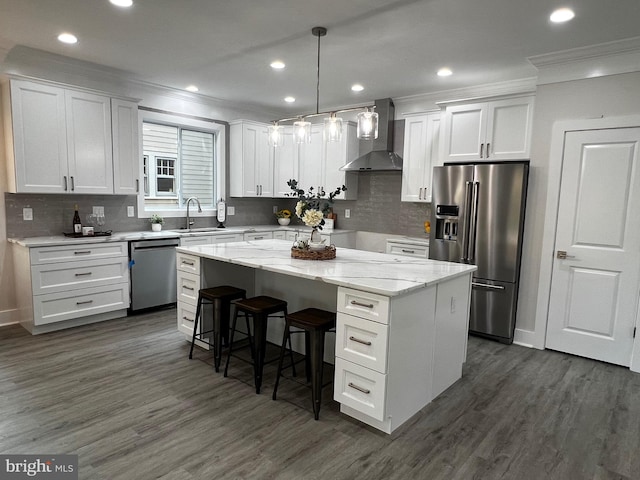 kitchen with stainless steel appliances, a kitchen island, white cabinetry, and wall chimney exhaust hood