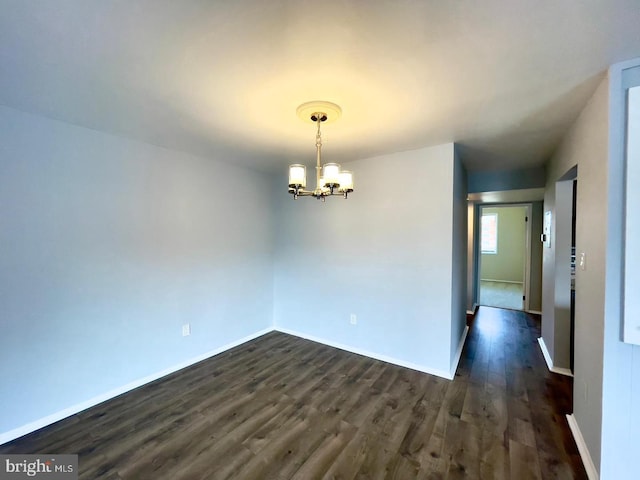 unfurnished room featuring dark hardwood / wood-style floors and an inviting chandelier