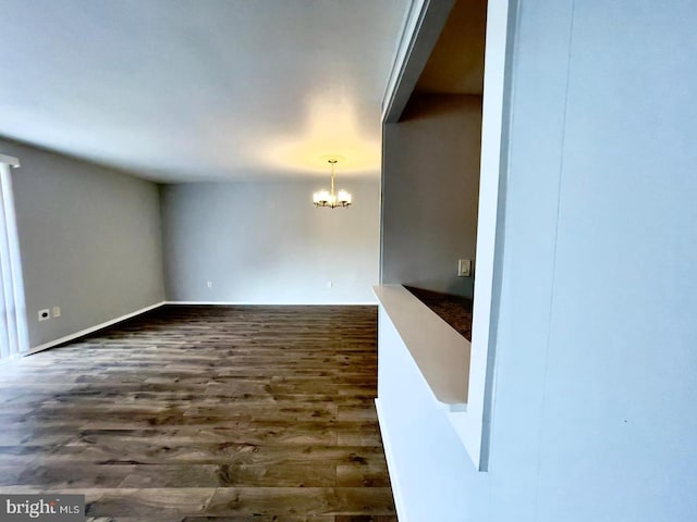 unfurnished living room with a notable chandelier and dark wood-type flooring