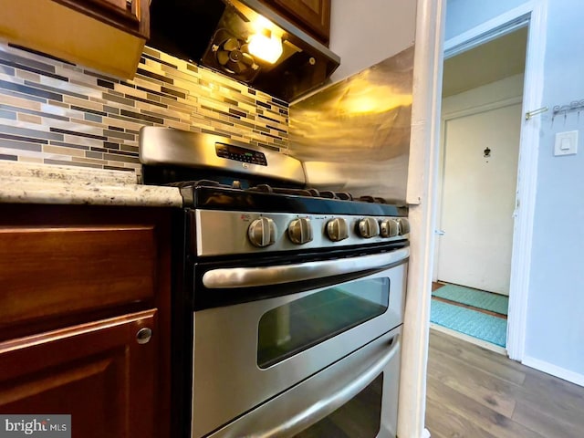 kitchen with decorative backsplash, stainless steel range with gas cooktop, and hardwood / wood-style floors