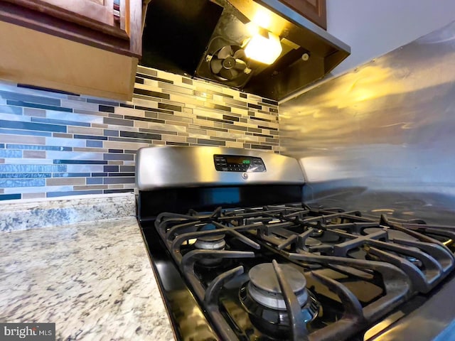 interior details featuring ventilation hood, gas stove, and tasteful backsplash