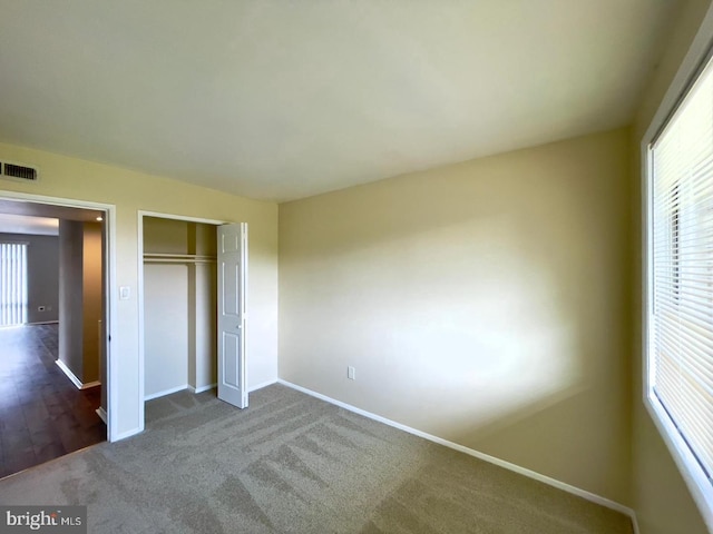 unfurnished bedroom with a closet and dark colored carpet