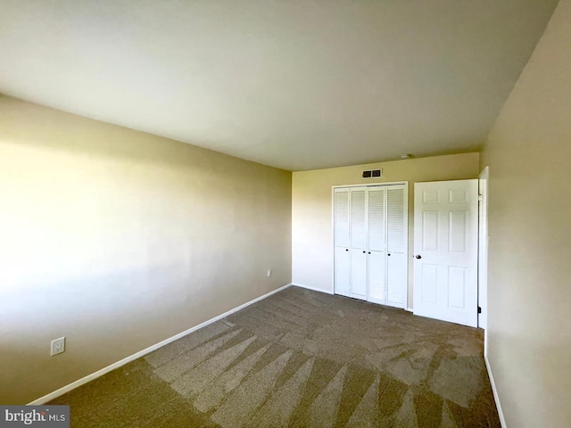 unfurnished bedroom featuring a closet and dark carpet