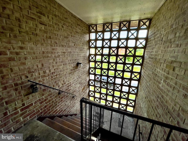 stairway featuring brick wall