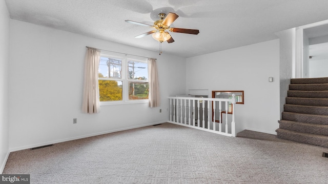 carpeted empty room with ceiling fan and a textured ceiling