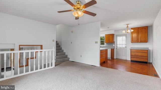 unfurnished living room with carpet flooring and ceiling fan with notable chandelier