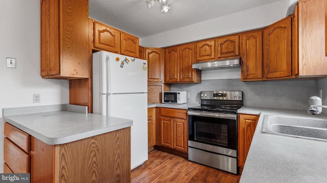 kitchen featuring sink, tasteful backsplash, a textured ceiling, white appliances, and light wood-type flooring