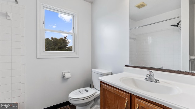 bathroom featuring tiled shower, vanity, and toilet