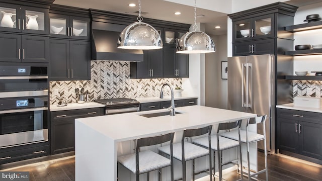 kitchen with a kitchen island with sink, sink, hanging light fixtures, dark hardwood / wood-style flooring, and stainless steel appliances