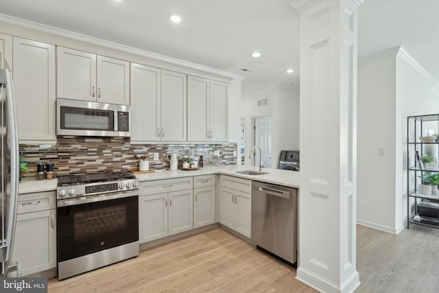 kitchen featuring sink, tasteful backsplash, light wood-type flooring, appliances with stainless steel finishes, and ornamental molding