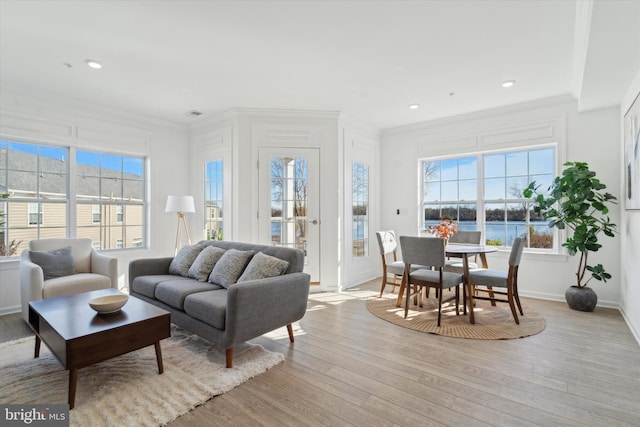 living room with a water view, ornamental molding, and light wood-type flooring