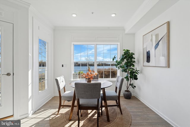 dining area featuring crown molding, plenty of natural light, a water view, and light hardwood / wood-style flooring