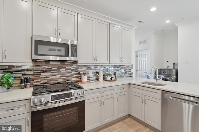 kitchen with appliances with stainless steel finishes, tasteful backsplash, crown molding, sink, and white cabinetry