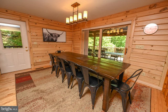 dining space with light hardwood / wood-style floors and wooden walls