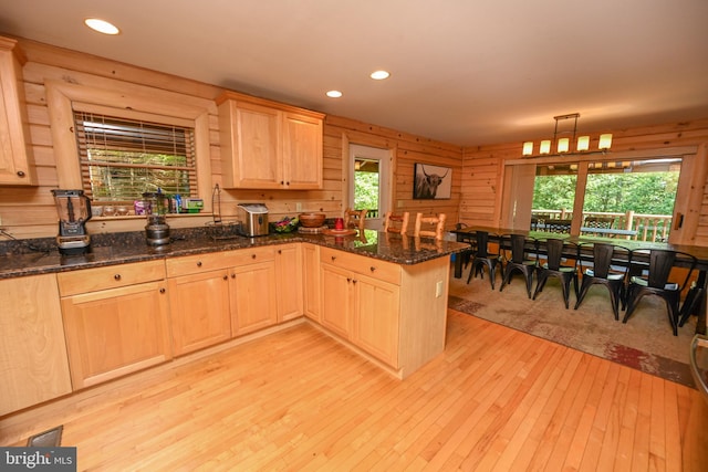 kitchen featuring a wealth of natural light, decorative light fixtures, kitchen peninsula, and wooden walls