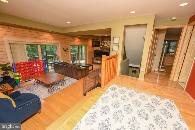 living room featuring wood-type flooring, a stone fireplace, and wood walls