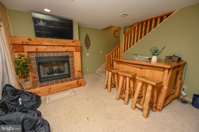 carpeted living room with bar and a tiled fireplace