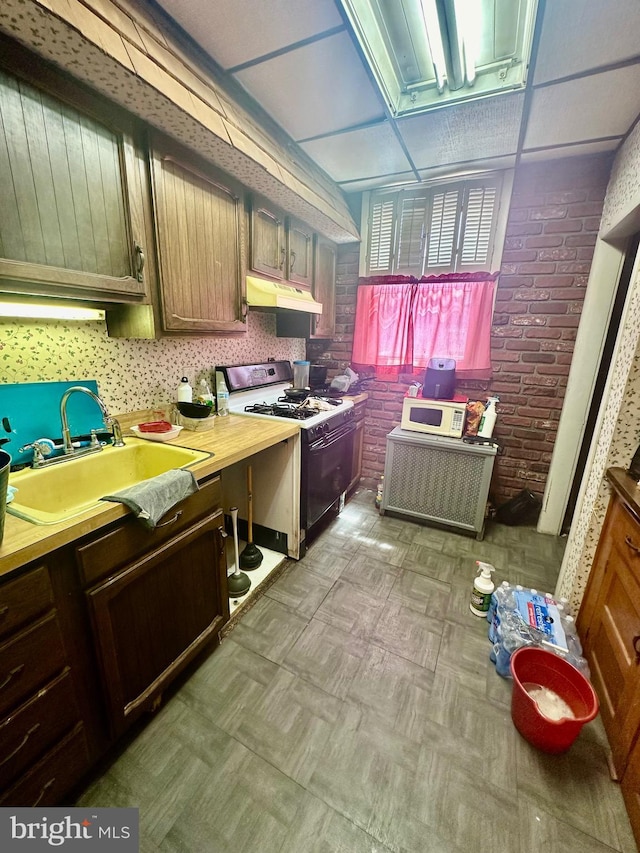 kitchen featuring sink, brick wall, and white appliances