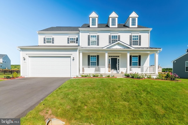 view of front of house featuring covered porch, a garage, and a front lawn